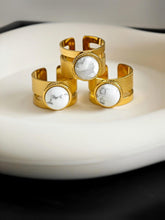 Goldener Ring mit moderner geometrischer Struktur und weiß-marmoriertem Stein